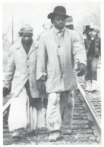 A boy and girl walk next to railroad tracks.