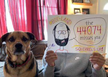 A man holds up a picture of himself with his dog sitting nearby
