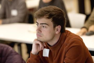 A student looks intently at a speaker in a classroom.