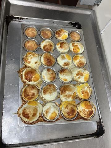 A muffin pan is pictured with cooked sunny-side up eggs in each compartment. 