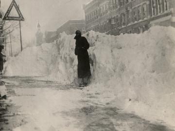 A man standing in front of a snow pile in downtown Oberlin.