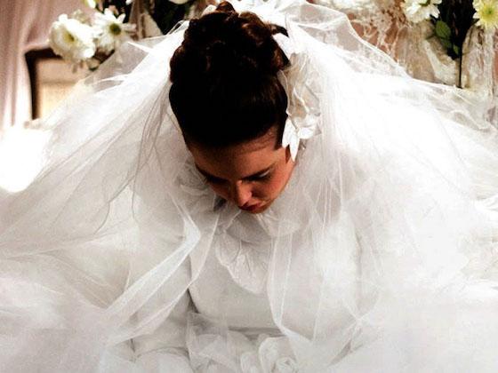 woman dressed in white wedding gown looking down.
