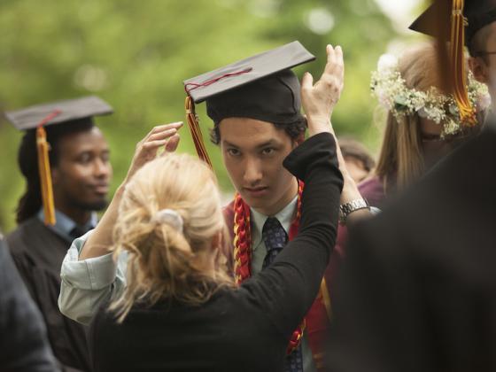 A mom adjusts her son's graduation cap.