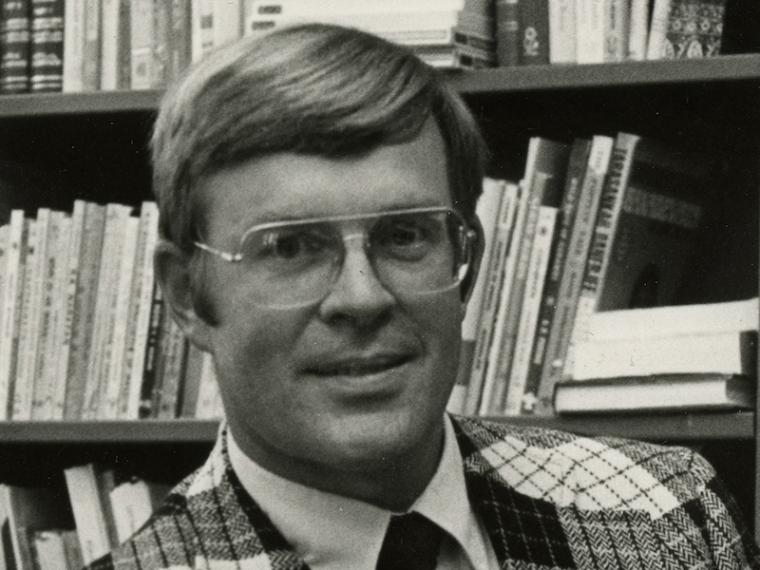 Larry Shinn posing in front of a bookshelf.