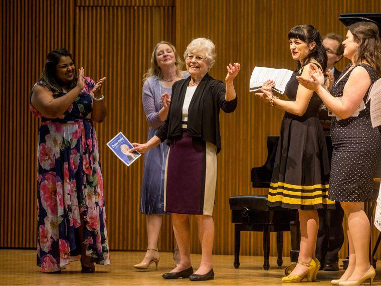 woman standing on stage receiving applause