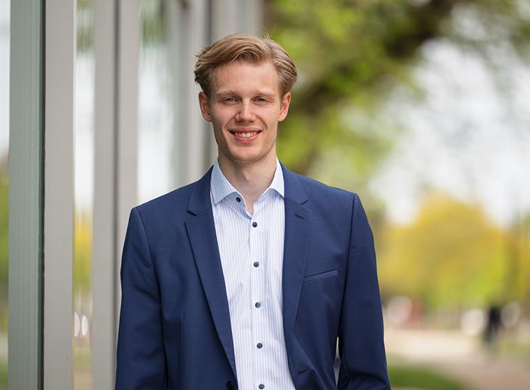 Student in blue jacket smiles outdoors