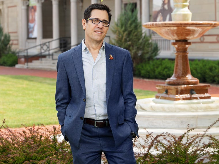 a person wearing a dark blue suit and light-colored shirt standing in front of an art museum