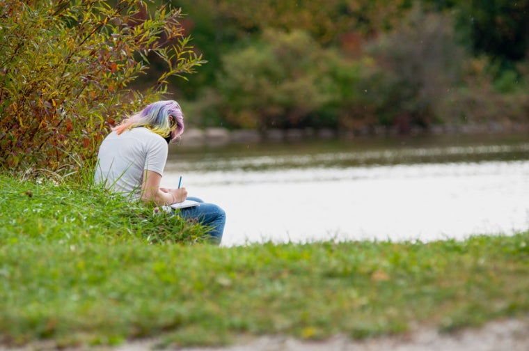 A student writes in the Arboretum