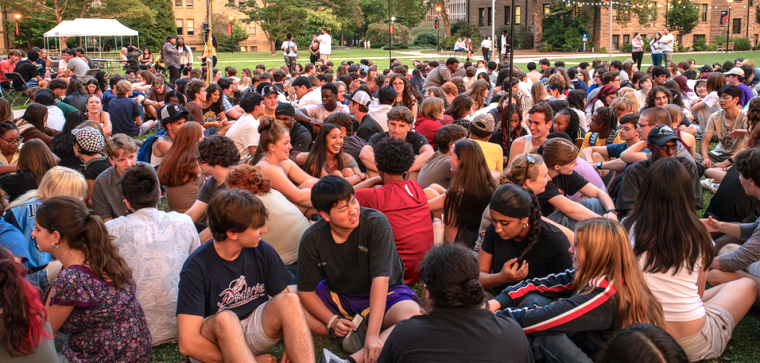 cheerful students gathered in a grassy area.