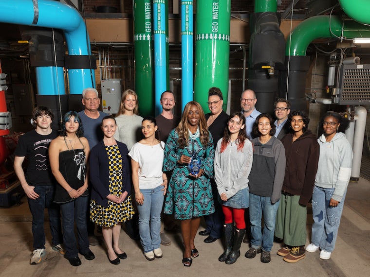 students and staff pose for a photo with a glass statue inside Oberlin's heating and cooling plant.