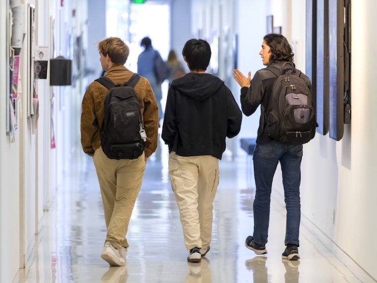 Three students walking down a hallway