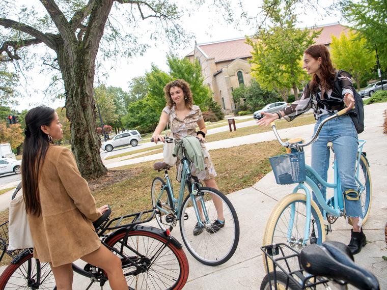 Three friends talk while seated on their bikes.
