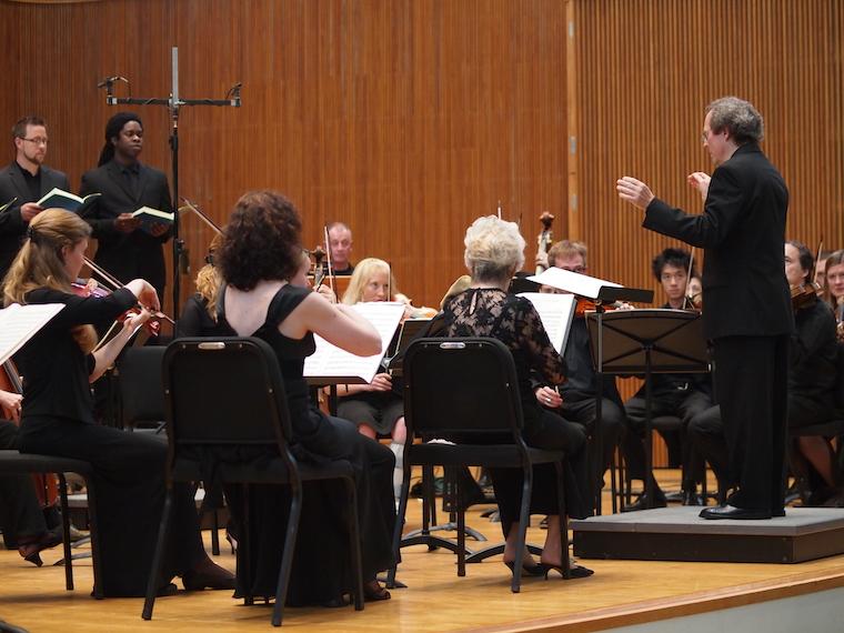 orchestra and singers on stage with conductor leading
