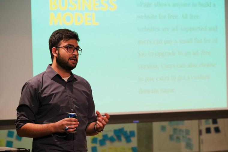 A male student makes a presentation, showing a slide about a business model.