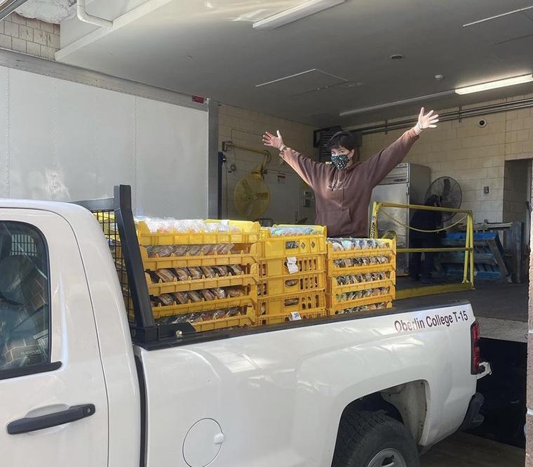 Masked student excitedly presents truck bed full of rescued food