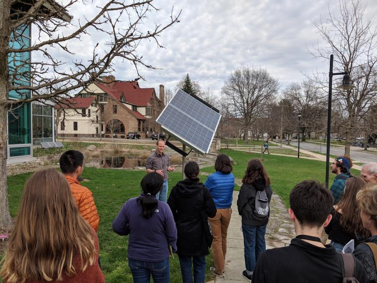 Professor John Petersen speaks to a class in front of the single mounted solar panel.