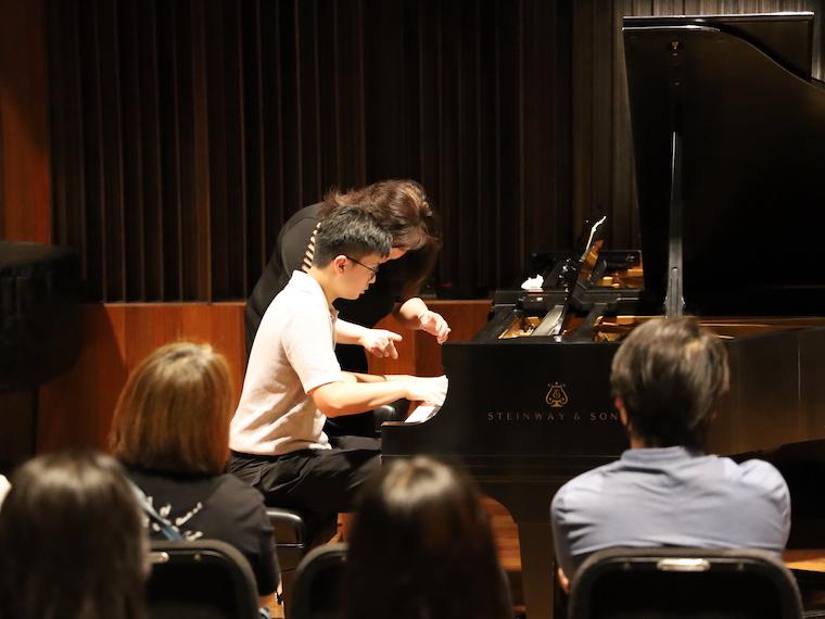 A young student works with a faculty member in a summer piano master class.
