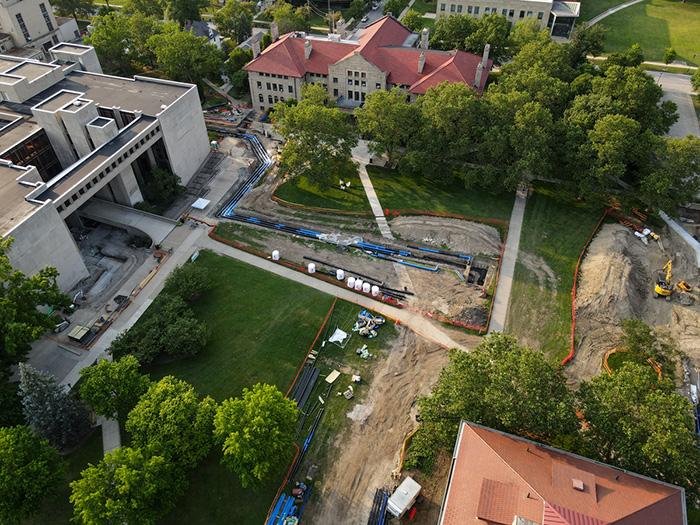 Aerial view of a campus quadrangle. A section is dug up, and long pipes lay on the ground.