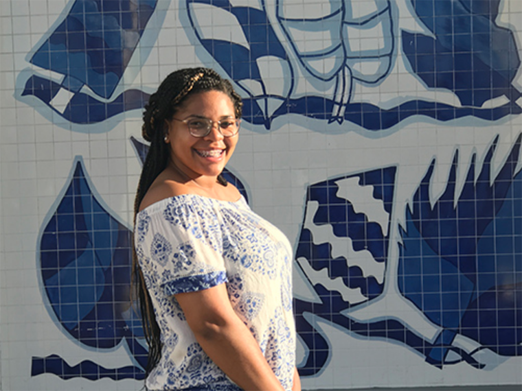 Woman standing in front of tile-covered wall.