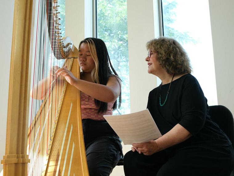 Instructor smiling at student playing harp