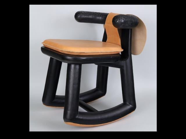 A wooden rocking chair with rounded and chunky legs and rockers, and a low back that curves into small armrests.