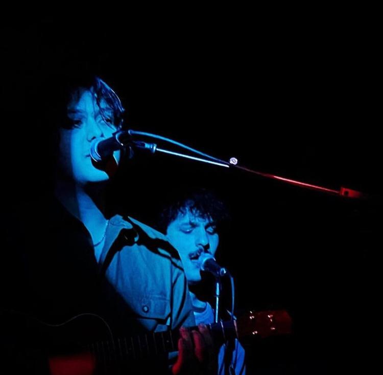 Two performers in dramatic blue light, singing into microphones