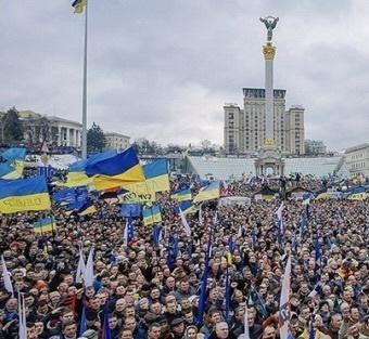 A large crowd in a square waiving Ukrainian flags 