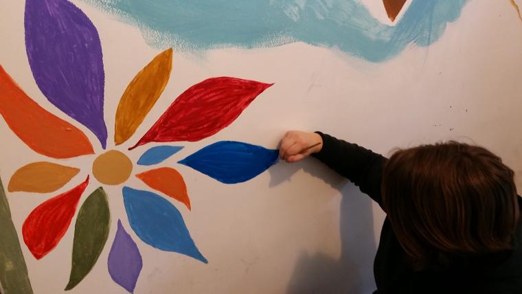 Student painting a flower on a wall 