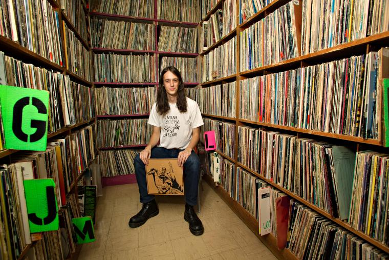 Adrian Rew ’13 surrounded by shelves full of LP records