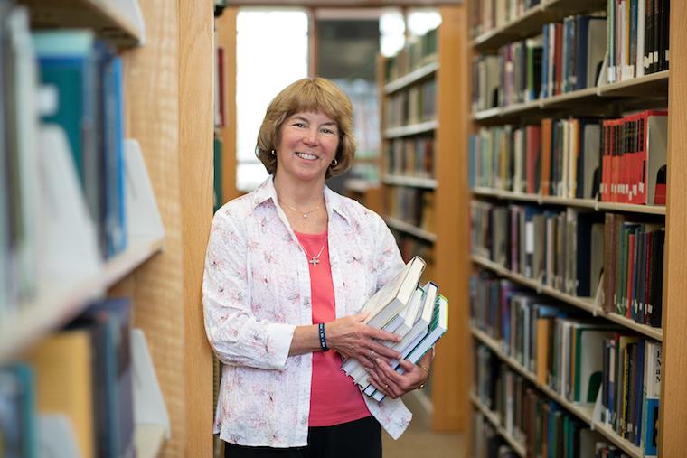 Picture of woman holding a stack of books in library