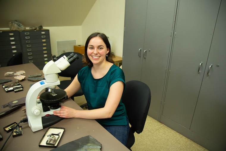 Amelia Lewis smiling, seated at a desk in the geology lab