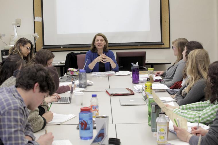 Ana Cara leads a discussion with students around a table.