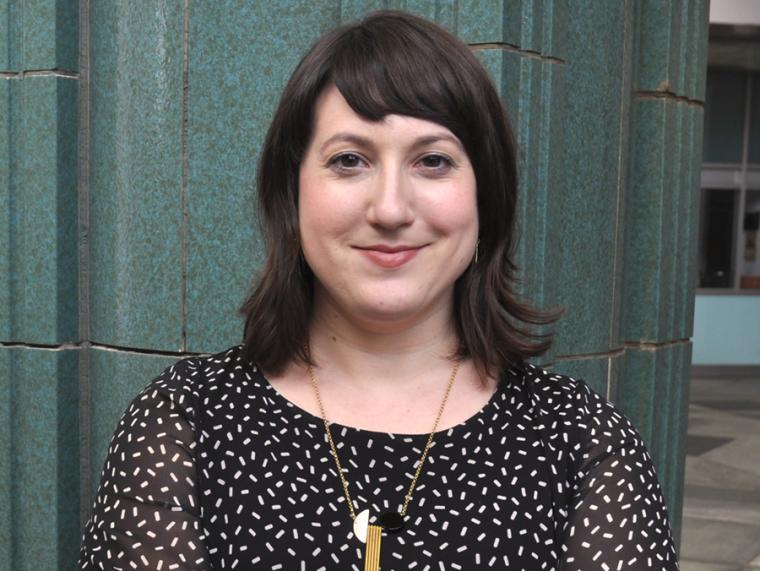 Portrait of Andrea Gyorody standing before a stone pillar in the museum