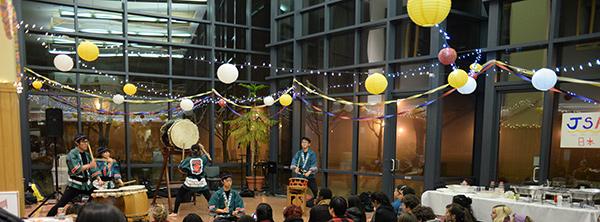 People watch Taiko drummers under festive decorations.