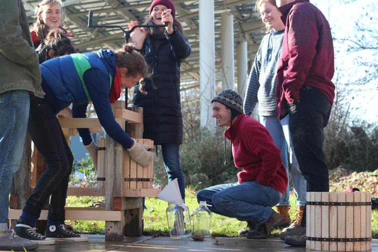 A group of students using a hand-cranked cider press.