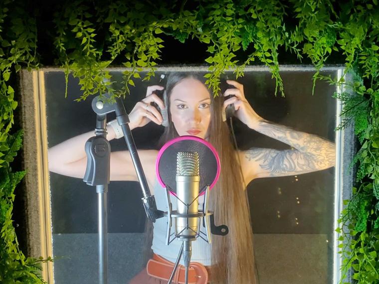 a person with long hair in a studio singing into a microphone