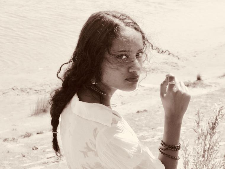 A sepia image of woman with long hairand white blouse facing forward.