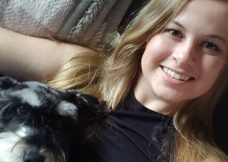 A girl cuddles with a small dog.