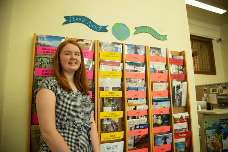 Picture of woman standing next to wall of brochures