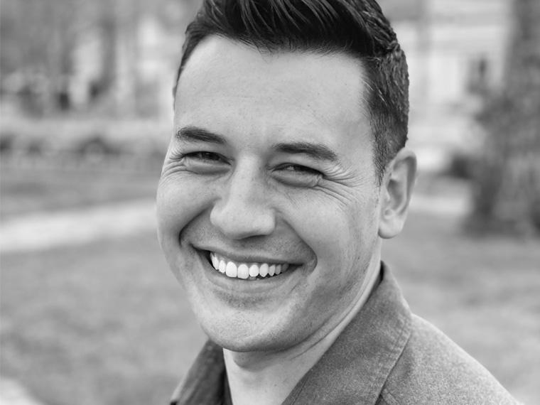 a headshot of a smiling person standing outside