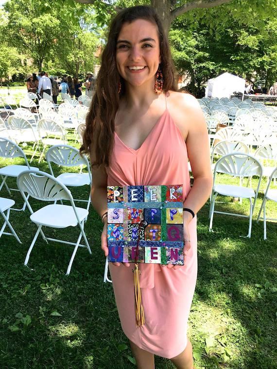 Charis Stanek standing at commencement, holding her graduation cap