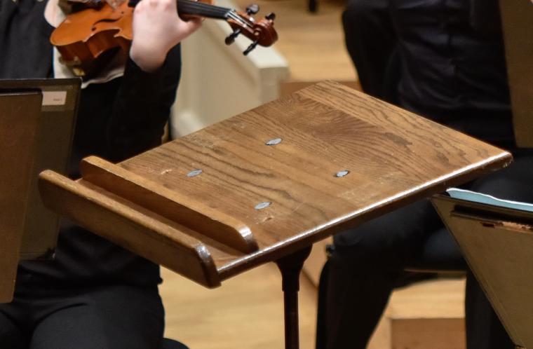 Closeup view of an empty podium. Musicians are partially visible in the background.