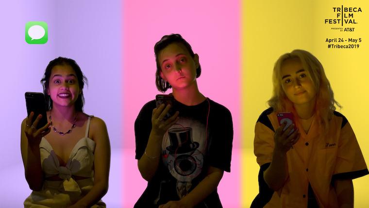 "CRSHD" movie still showing three main actresses looking at the camera, holding their phones, against purple, pink, and yellow background
