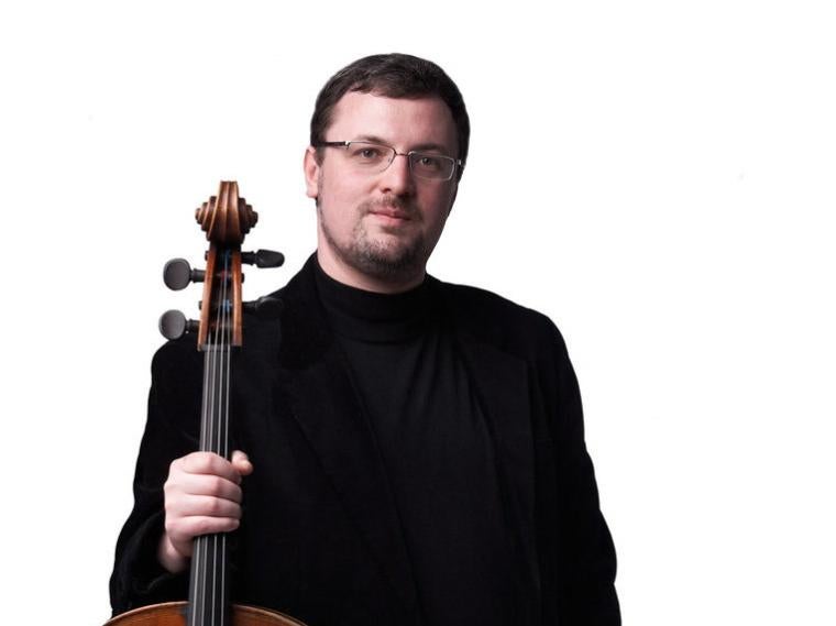 cello faculty member Dmitri Kouzov holding his cello.
