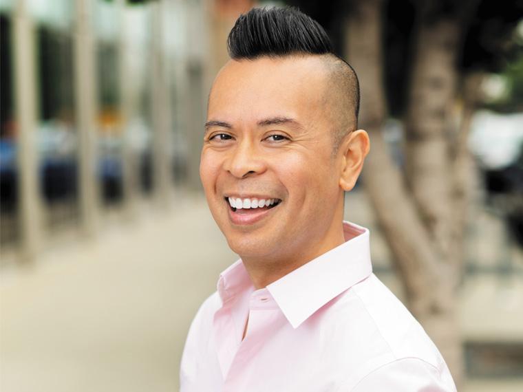 a person wearing a light pink collared shirt smiles for the camera