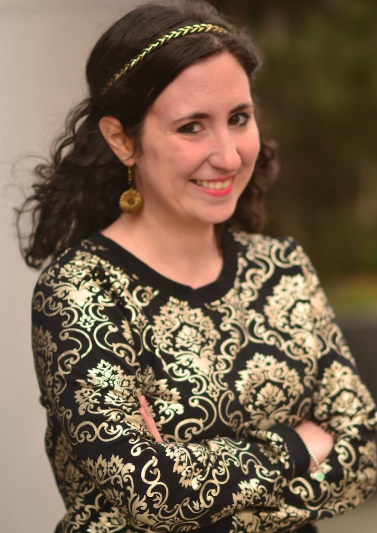 A woman smiles with arms folded