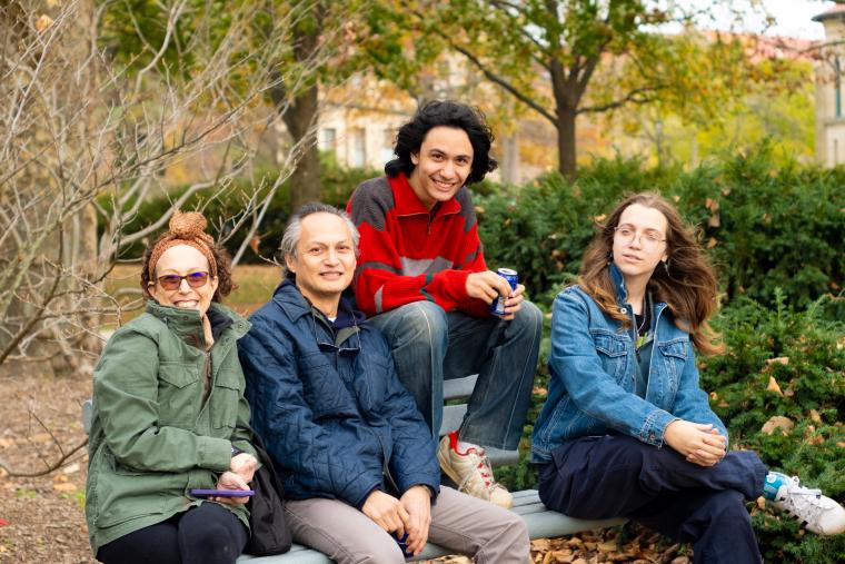 A family sitting on a bench and smiling for the camera