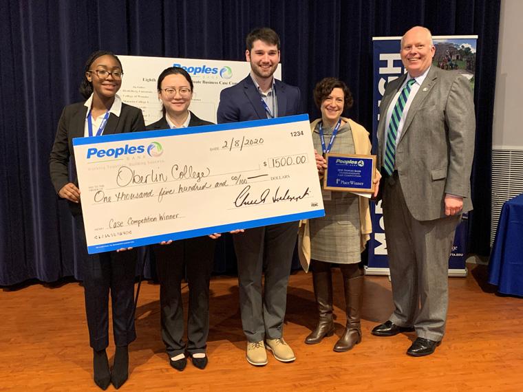 students and advisor standing and holding a check.