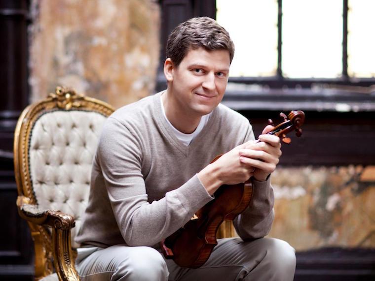 man sitting in cushioned chair holding violin