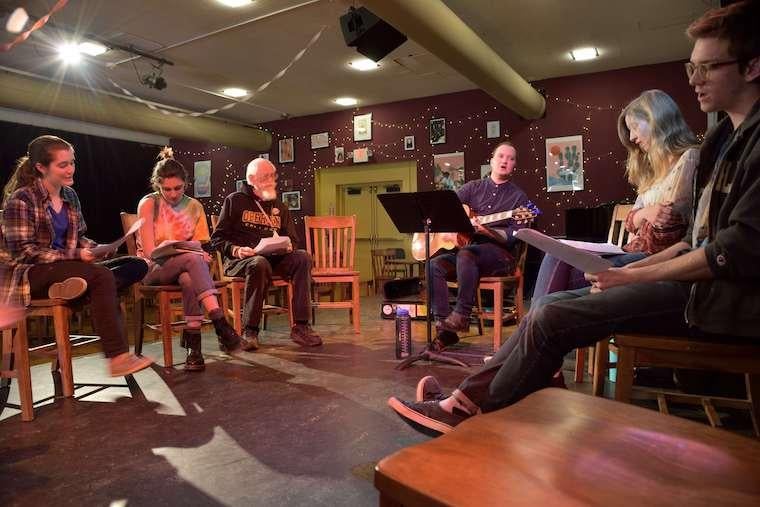 Picture of people sitting in a circle around a person playing guitar